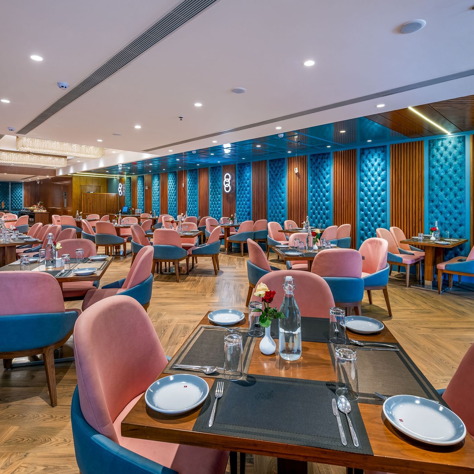 Blue Corainder with pink chairs, black tables, and ambient lighting