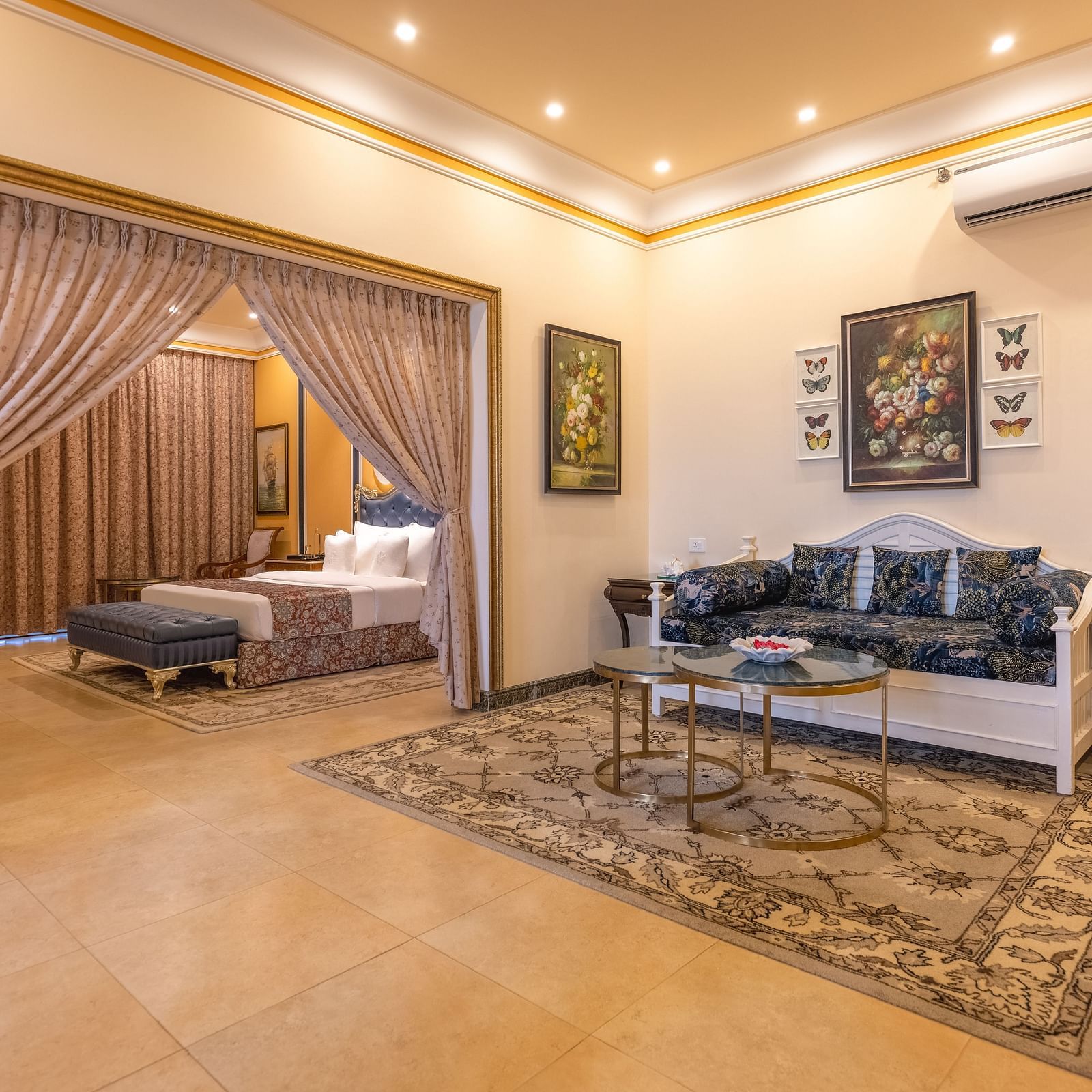 A double bedroom, with a separate living space with sofa and a coffee table and a wall-mounted air-conditioner at MAYFAIR Palm Beach Resort, Gopalpur-On-Sea