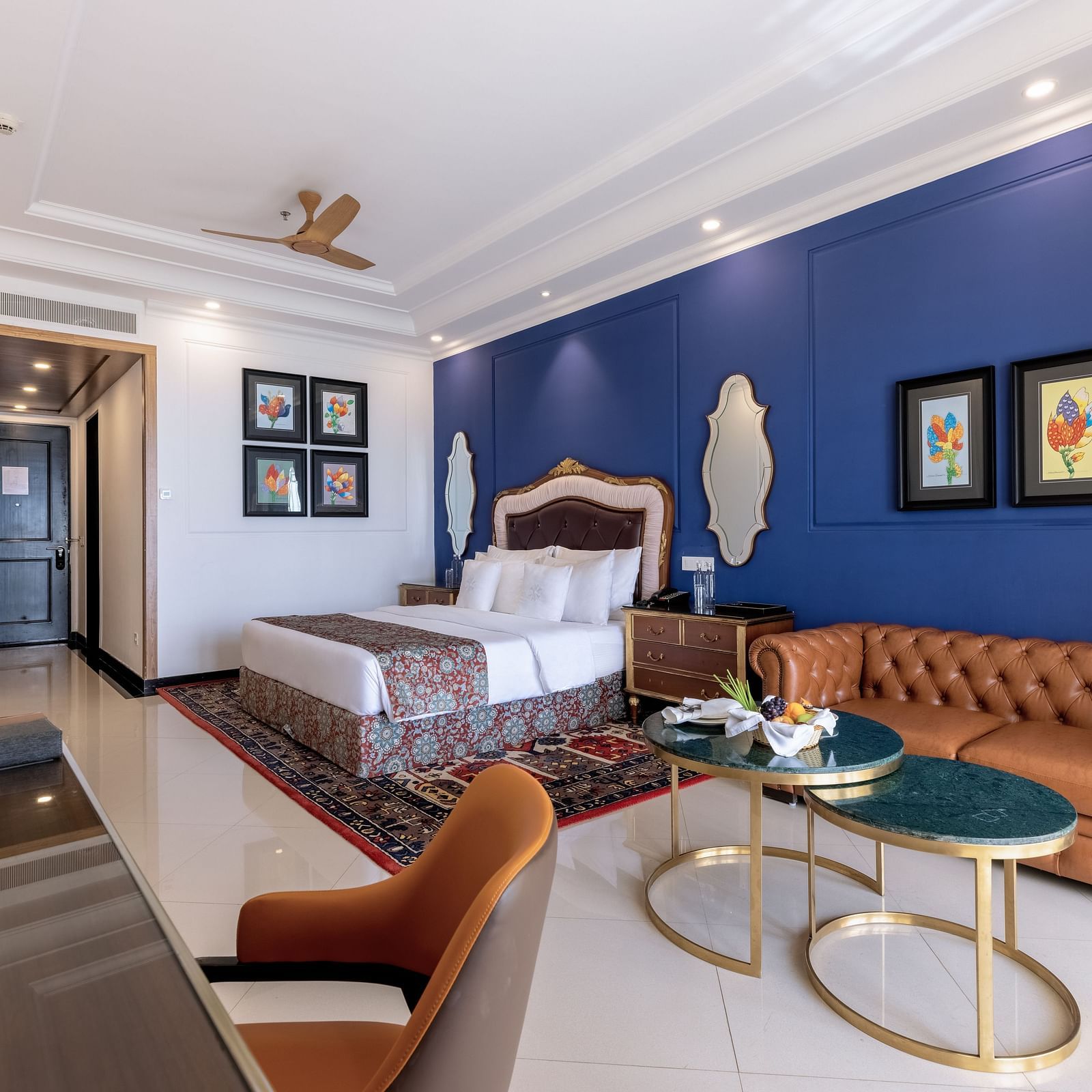 Double bed room with seating area, a workstation, a ceiling fan, and a wall-mounted TV at MAYFAIR Palm Beach Resort, Gopalpur-On-Sea