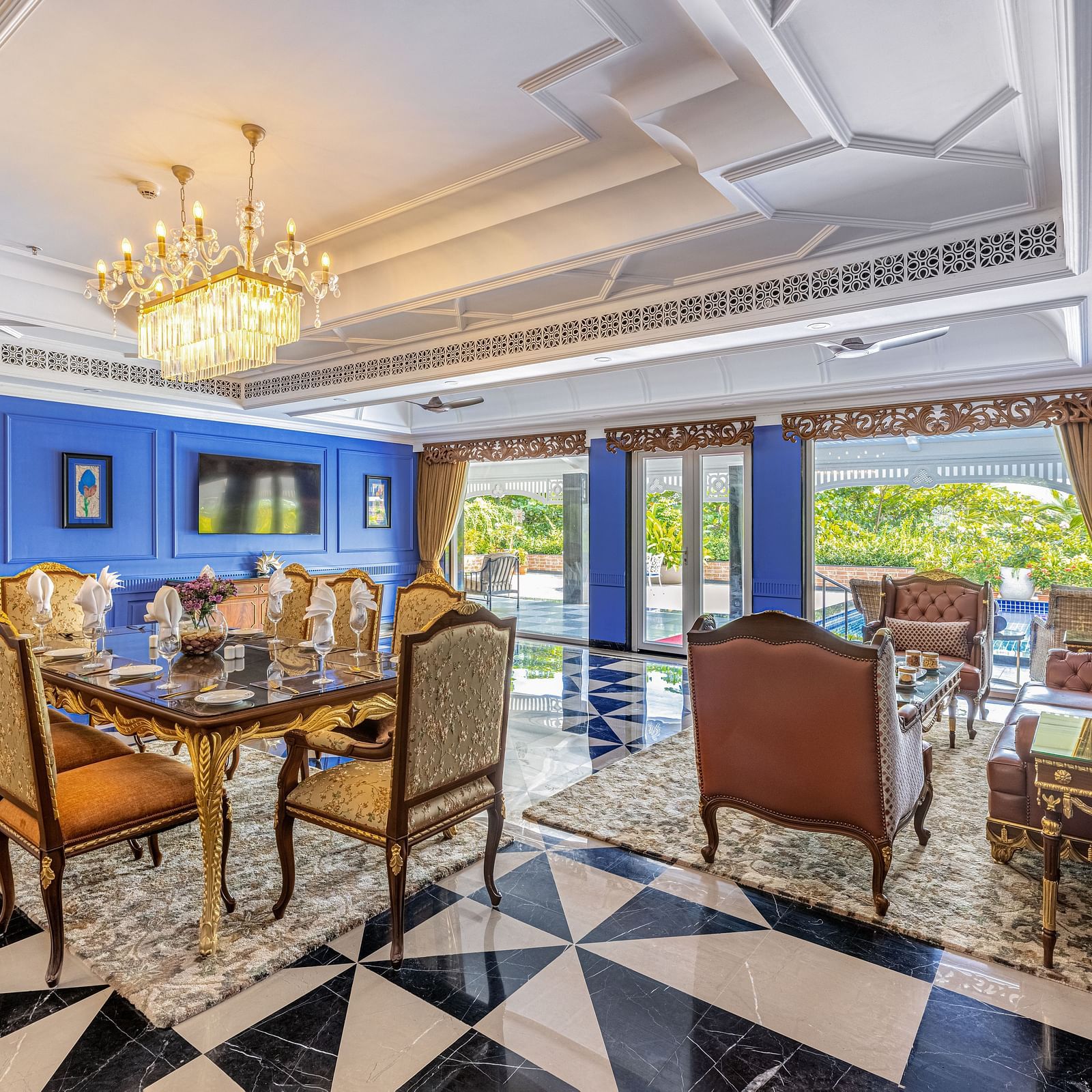 Luxurious dining and lounge area with royal blue walls, ornate chandelier, black-and-white checkered floor, and elegant furniture at MAYFAIR Palm Beach Resort, Gopalpur-On-Sea