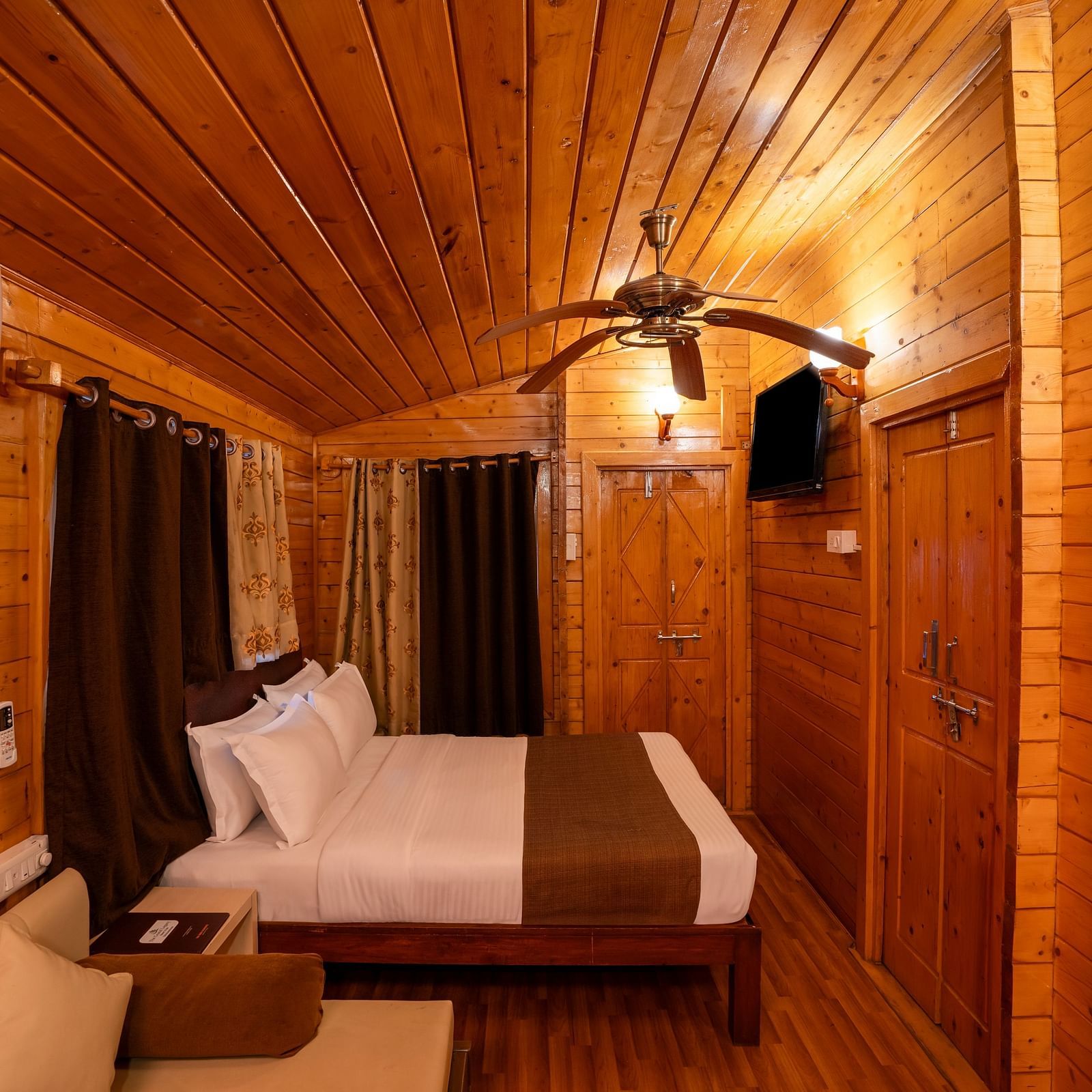 Image of orion suite with wooden furnishing featuring a king size bed and other amenities like couch and air conditioning | The Grand Legacy Resort and Spa