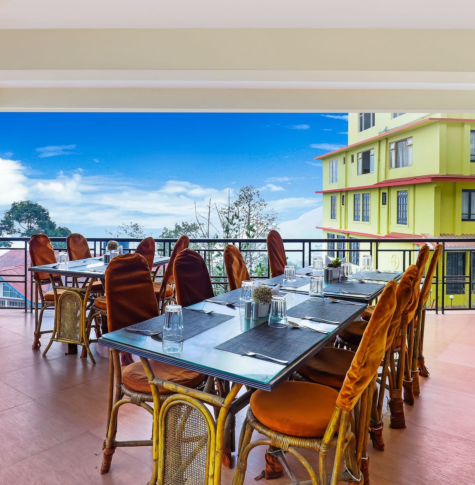 A dining table with multiple chairs placed in the balcony with a backdrop of blue sky | Summit Newa Regency & Spa, Pelling