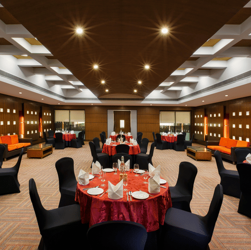 An overview of a banquet hall with circular tables with chairs arranged for an event - Heritage Village Resorts & Spa, Manesar.