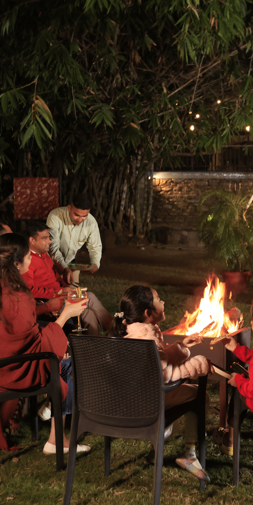 A group of poeple enjoying a bonfire evening outdoors at The Golden Tusk, Jim Corbett.