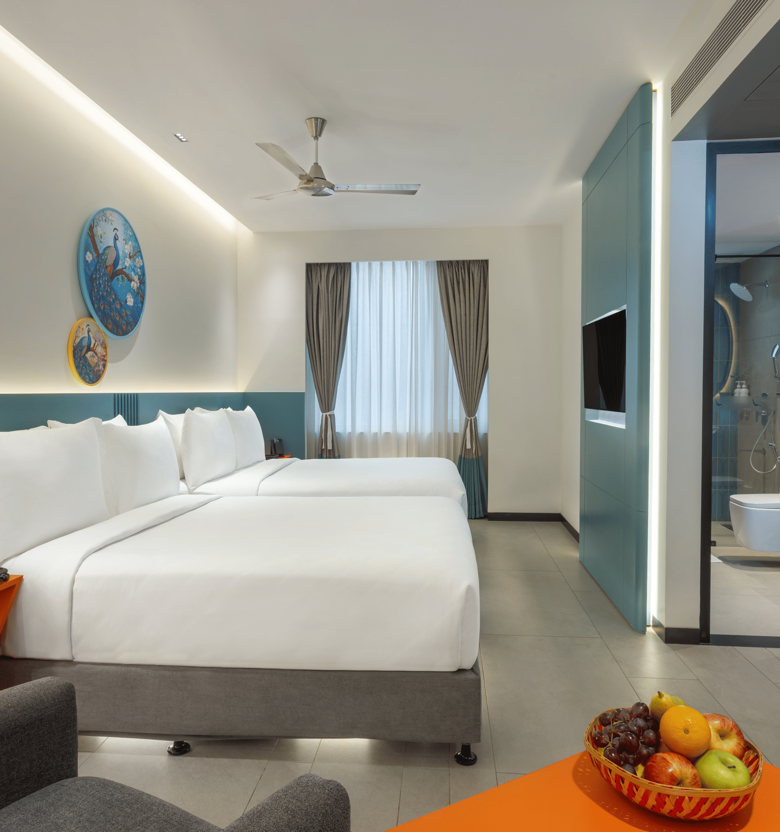 One of Zibe's hotel room in JP Nagar, Hyderabad, featuring twin beds, an attached washroom, a wall-mounted television, and a night stand.