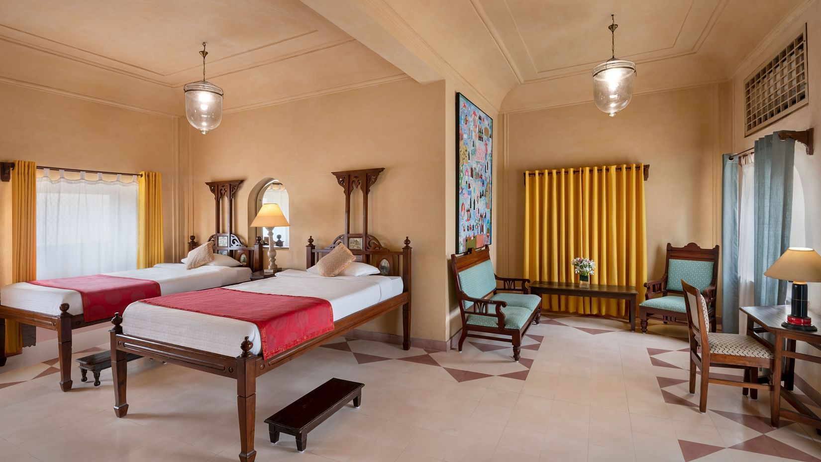 A room with two single beds, chairs, a desk, and a small bench in Tijara Fort-Palace - 19th Century, Alwar.