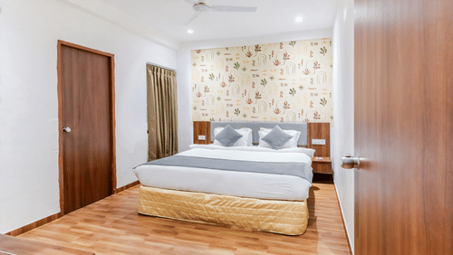 Suite at Pride Elite Wellness Resort Becharaji, Gujarat featuring a plush bed on wooden furnished floor with two nightstands on both sides