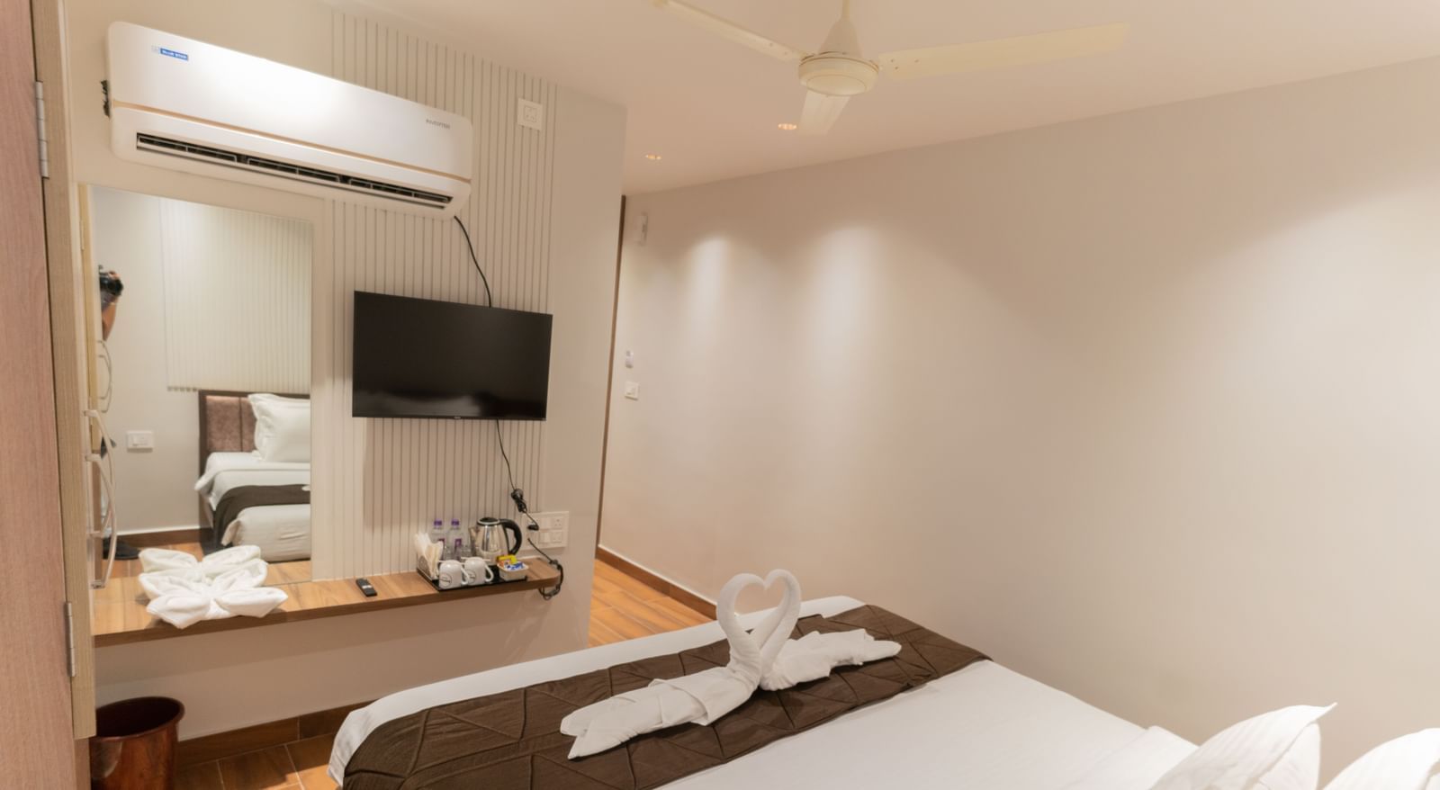 Modern bedroom with double bed, TV, and work desk featuring minimal decor at Beestay Hotels, Rajahmundry.