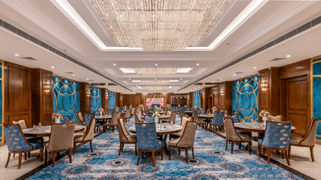 Elegant Banquet with blue-patterned carpet, wooden walls, and chandelier lighting.