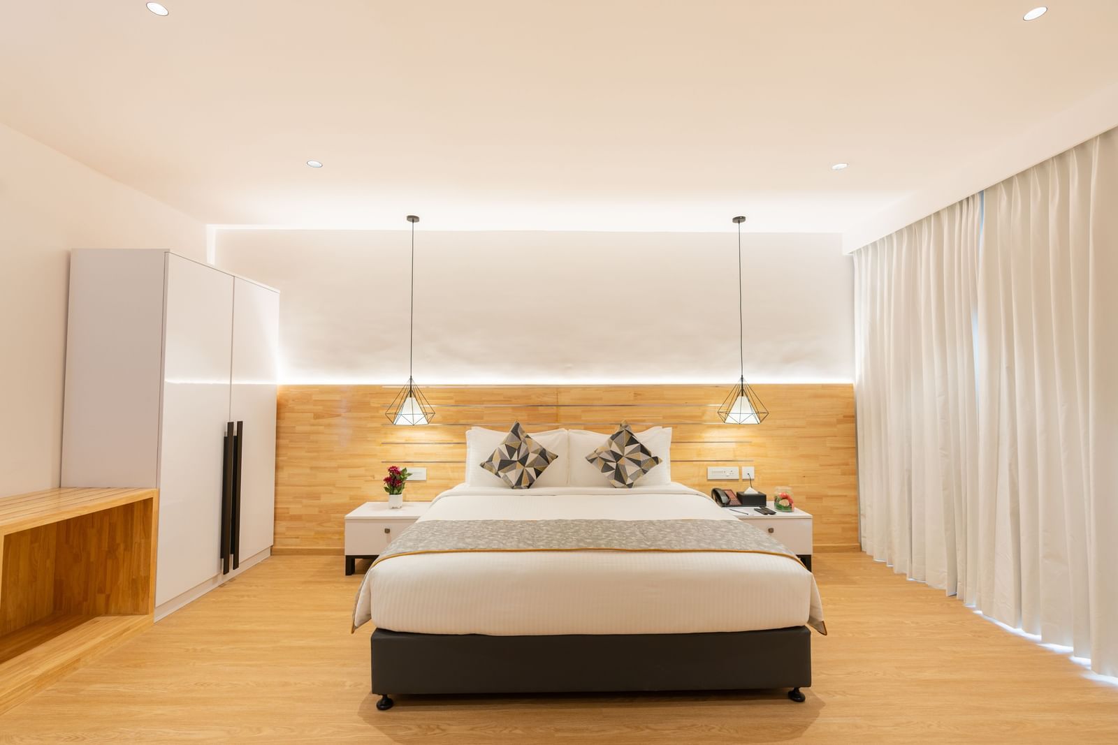 front view image of the garden view room that highlights a double bed along with two lights hanging from the ceiling above the bed side tables - Darza Resorts