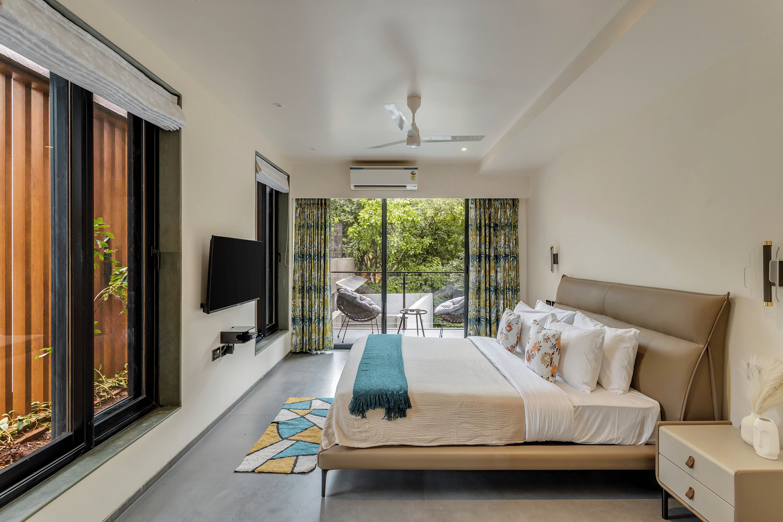  A side angle view of a bedroom at Lindsay Manor, featuring a bed, a window with a scenic view, and an LCD TV.