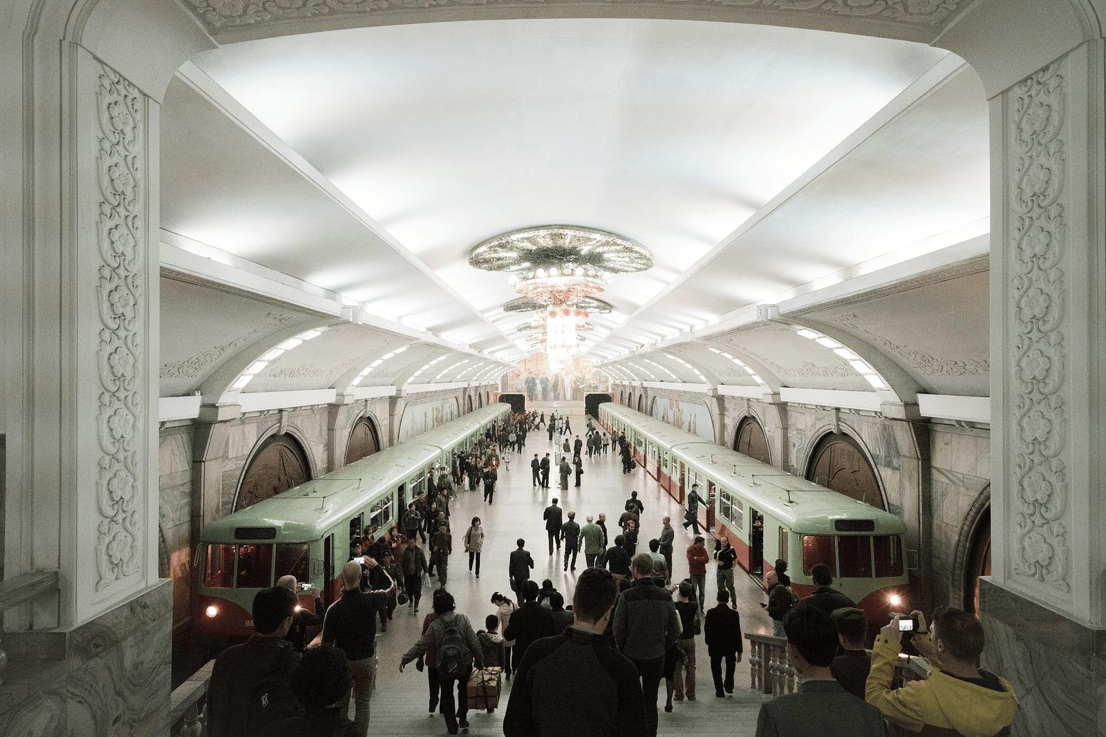 An overview of a metro station with people thronging towards the trains