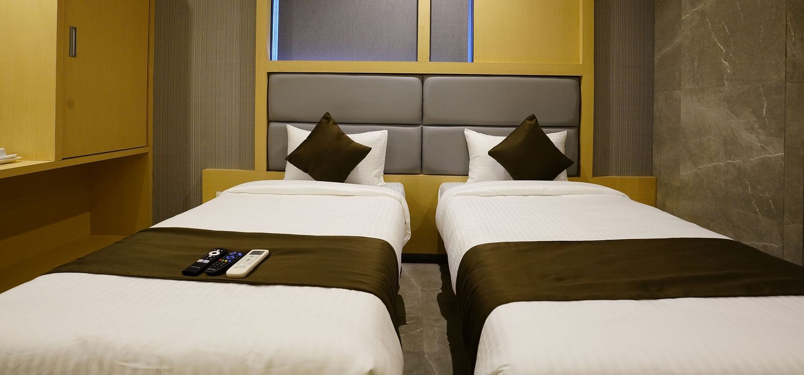 Hotel room with two single beds, wardrobes, and overhead lighting - Shyanu Lords Eco Inn Airoli
