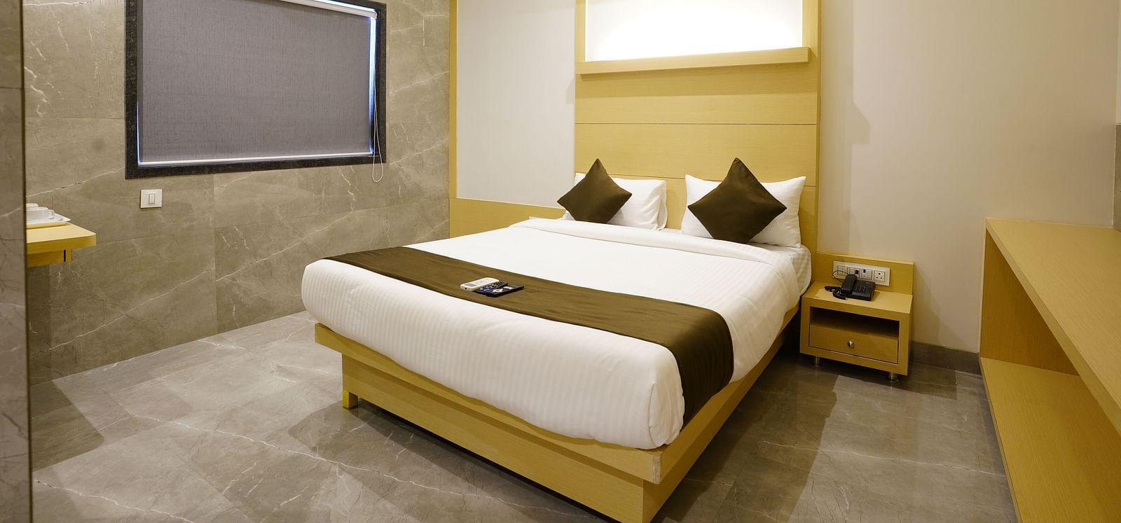 Hotel room with a double bed, white linens, brown runner, two brown pillows, and a wall-mounted television and AC - Shyanu Lords Eco Inn Airoli