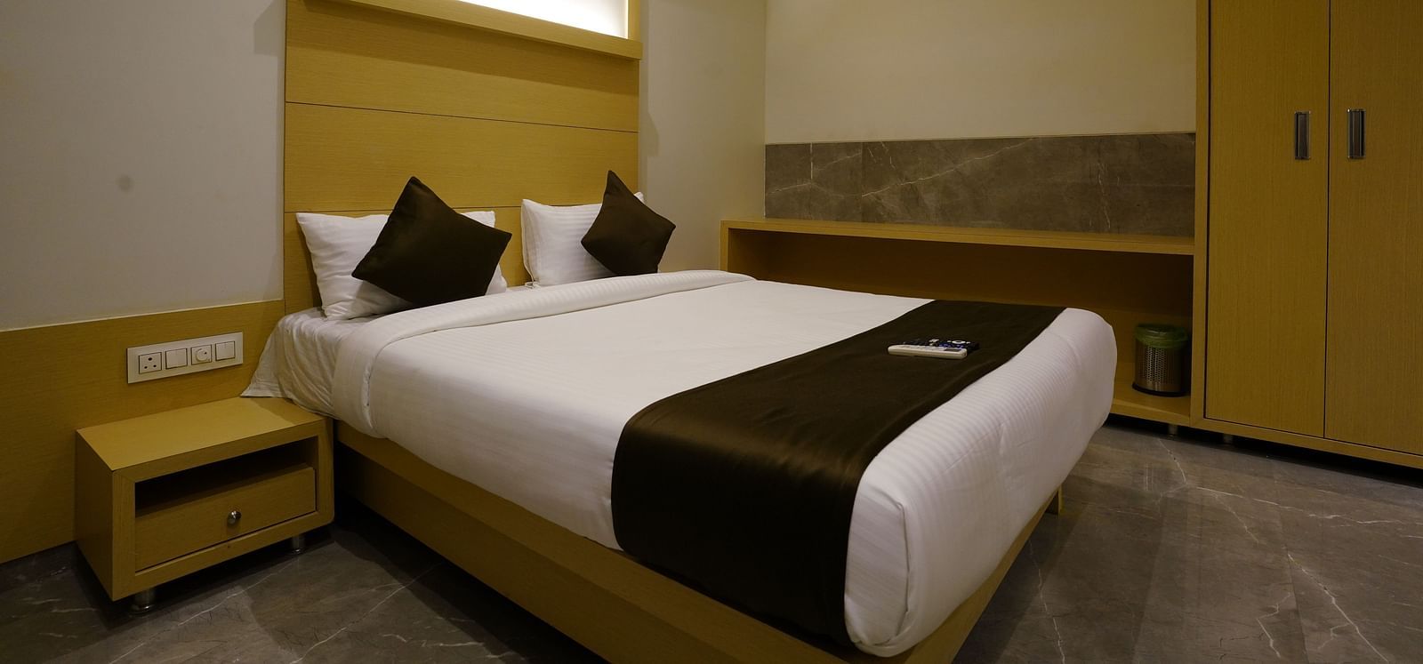 Hotel room with a double bed, bedside table, and warm lighting - Shyanu Lords Eco Inn Airoli