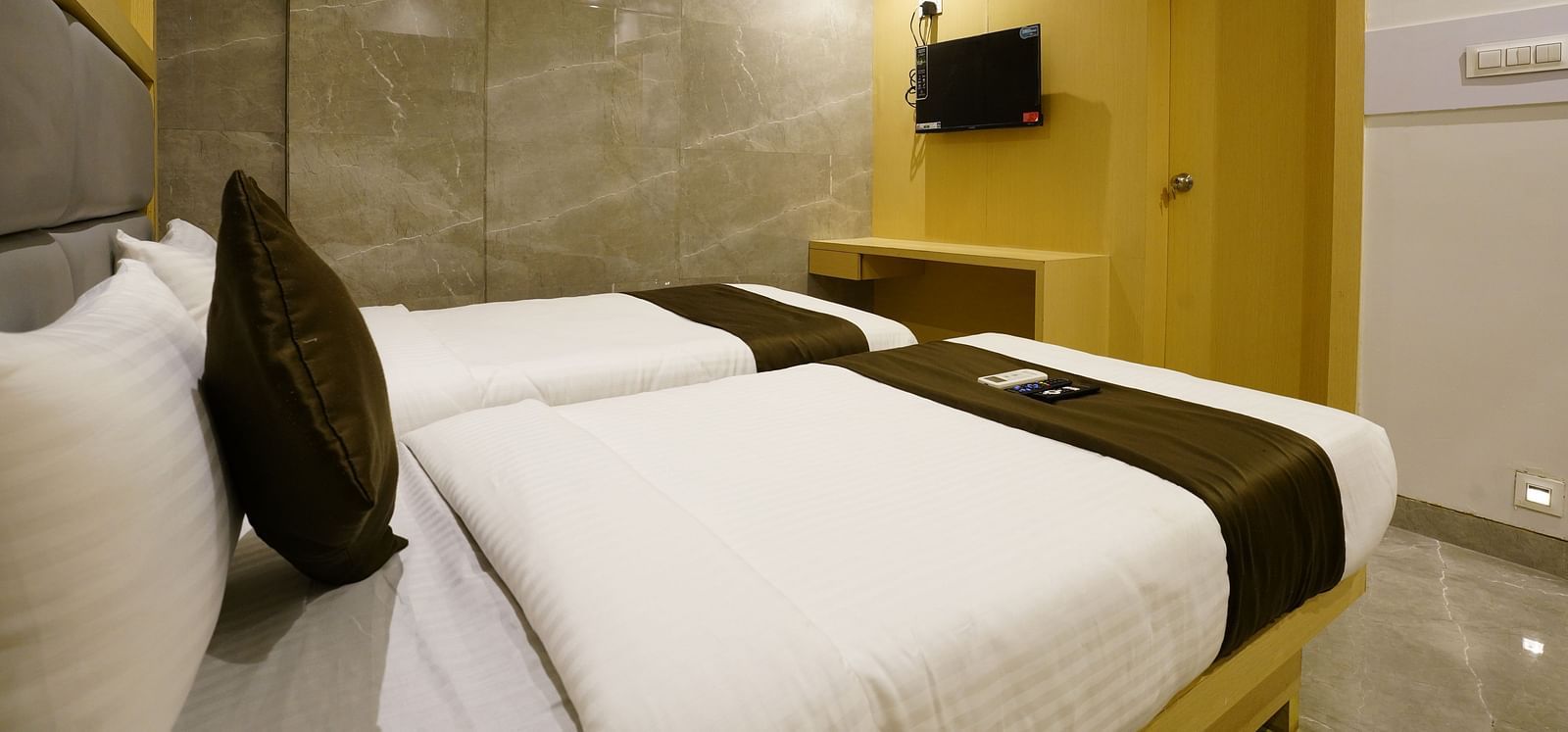 Hotel room with two single beds, white linens, brown runners, and a wall-mounted television - Shyanu Lords Eco Inn Airoli