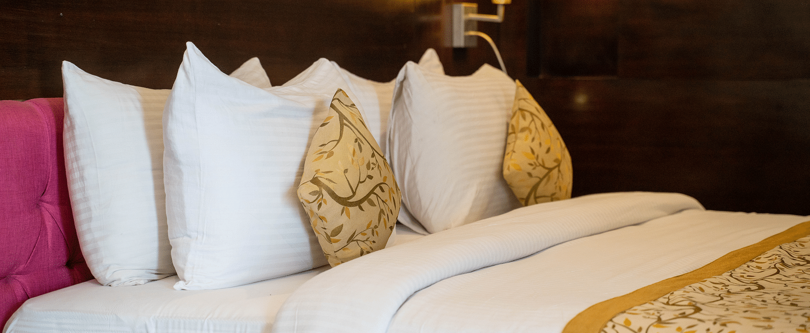 A luxurious hotel bed with plush pillows, gold-accented linens, and ambient lighting - Hotel Udai Median, Udaipur.