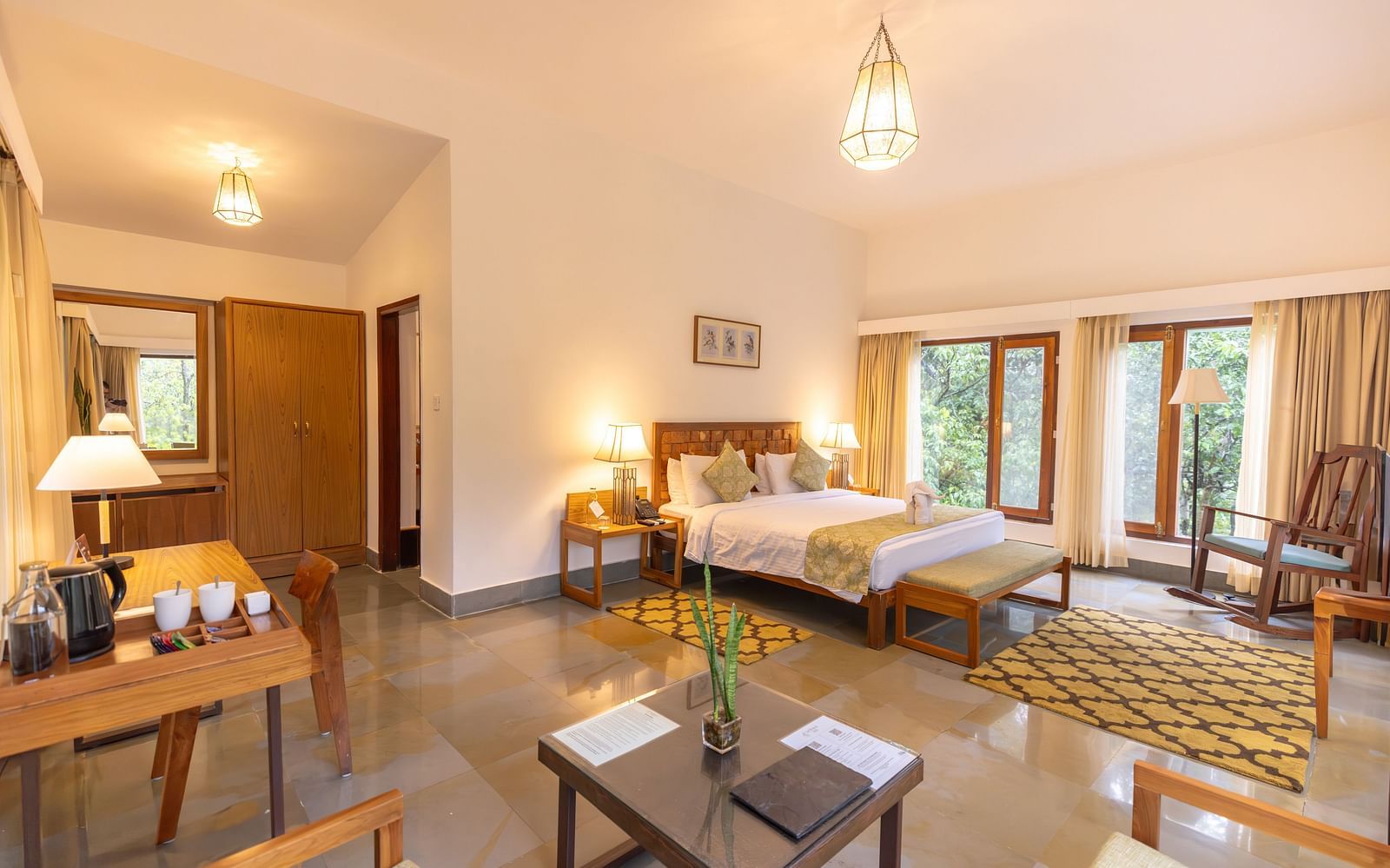 Premium Suite at Saraca Resort & Spa Corbett with a double bed, a sofa chair, a work desk and chair and a chandelier