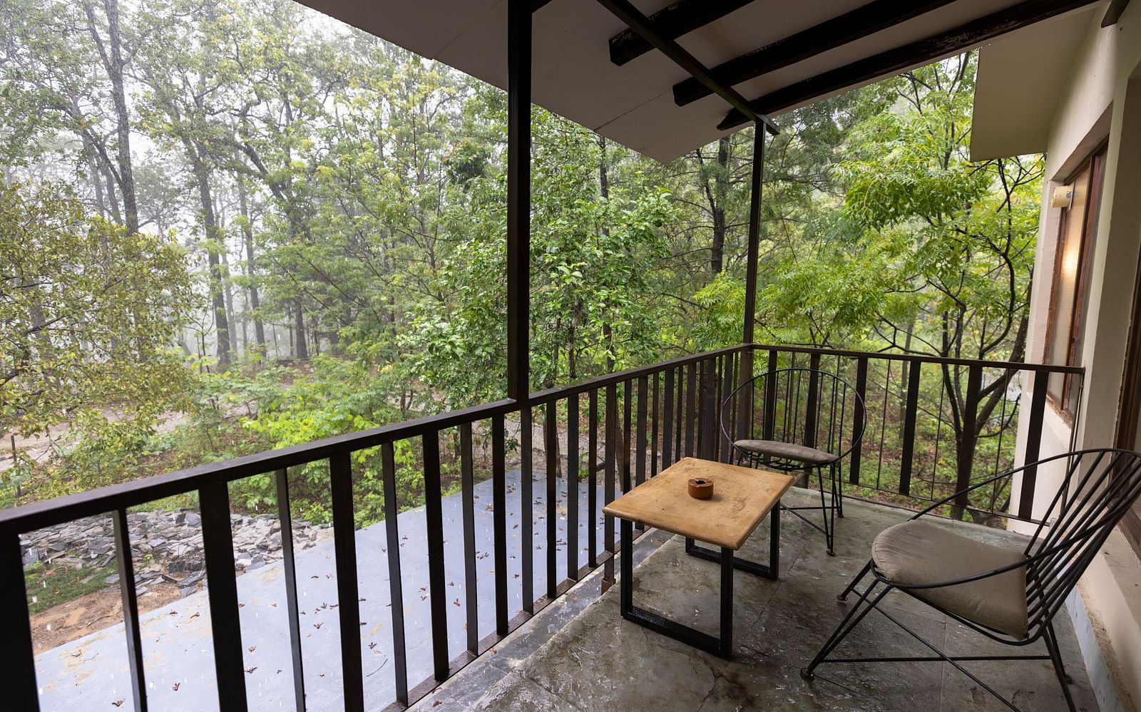 Private sit out area at Saraca Resort & Spa Corbett with a lounging chair and a coffee table overlooking the gardens on a foggy day