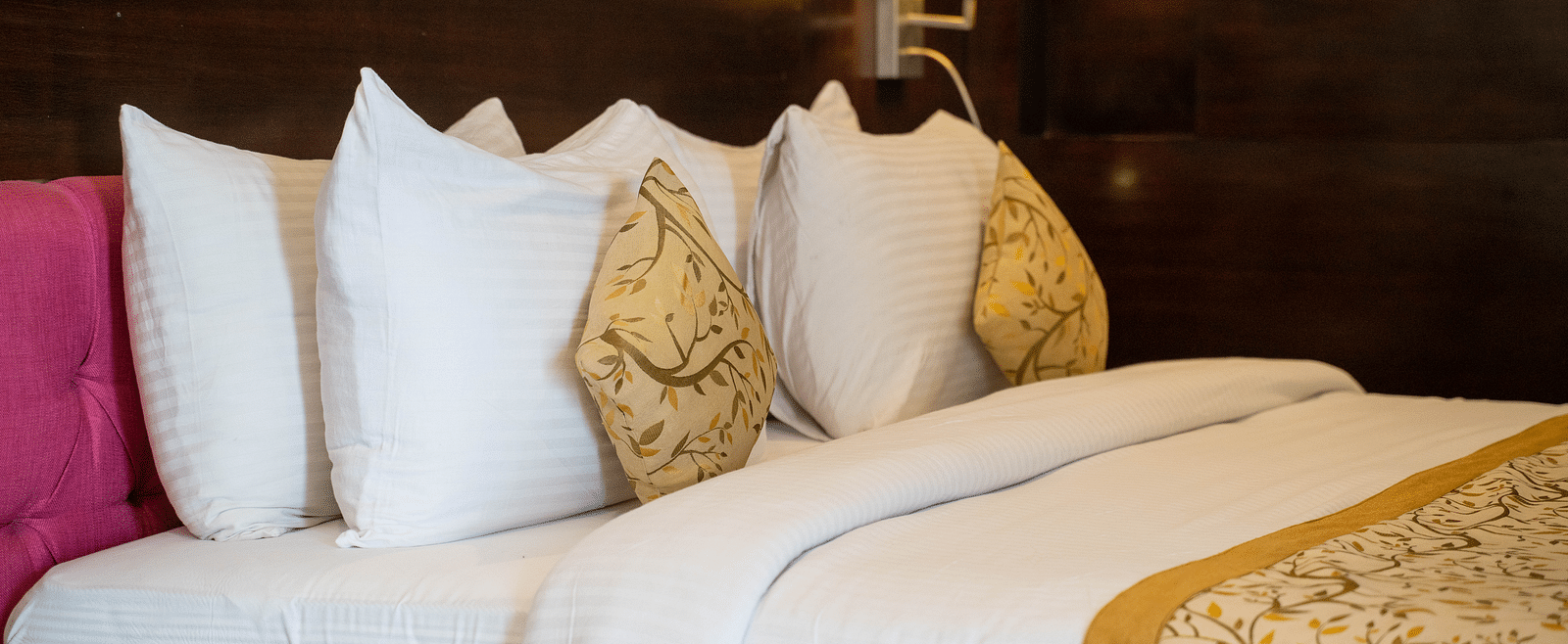 A luxurious hotel bed with plush pillows, gold-accented linens, and ambient lighting - Hotel Udai Median, Udaipur.