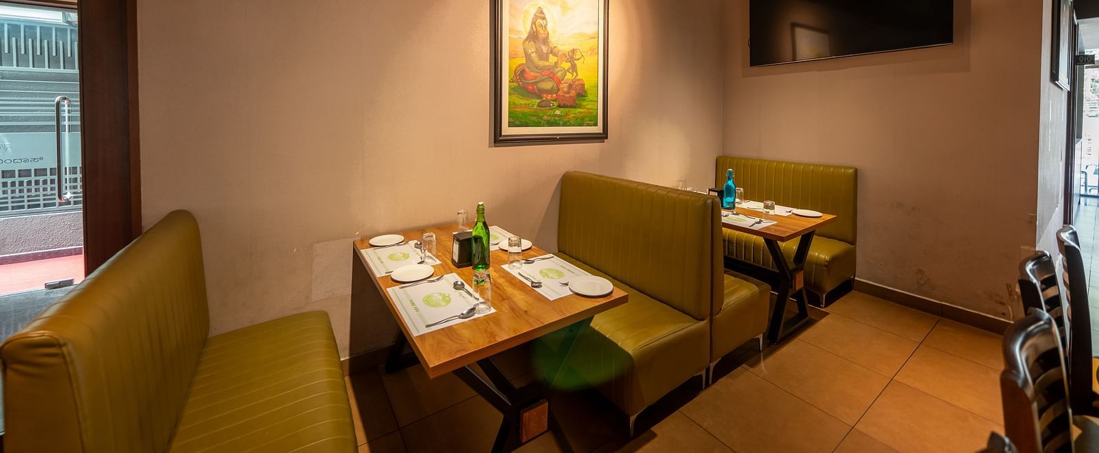 Image of a dining section with seating area and a photo frame mounted on the wall at Hari Govindas, Siddappa Square.