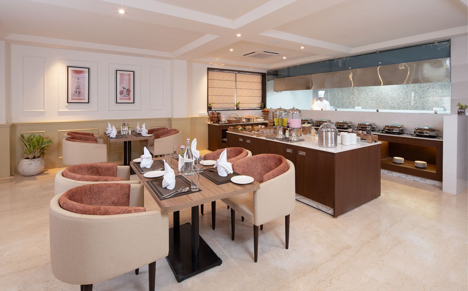 An image of a dining space with sofa chairs, centre table with hand towels and cutlery, and a buffet served at one corner - Brij Eternity, Vrindavan