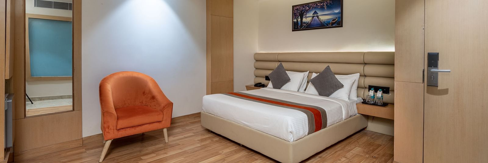 The deluxe room at DLS Hotel Arihant, Haridwar with a bed, bed side tables, a chair, and other room amenities