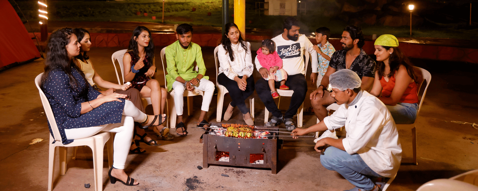 A group of people enjoying a bonfire in Pune at a camping site in the evening at Diamond Parks, Pune