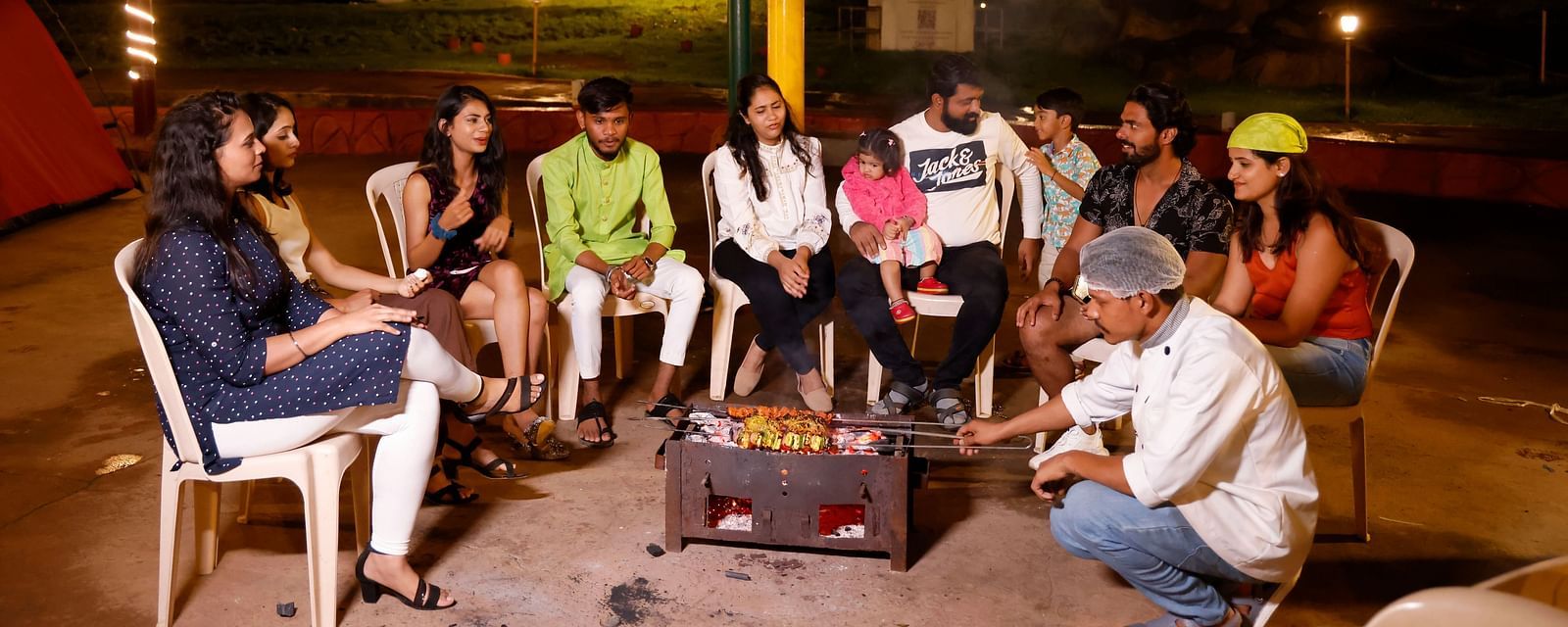 Group of friends enjoying a bonfire at a camping site in the evening | Diamond Parks, Pune
