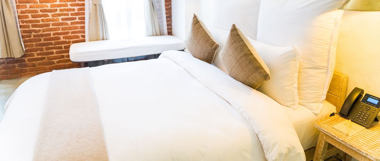 The deluxe loft room with a bed, bed side table, with a telephone places on it, and lamps - The Nanee
