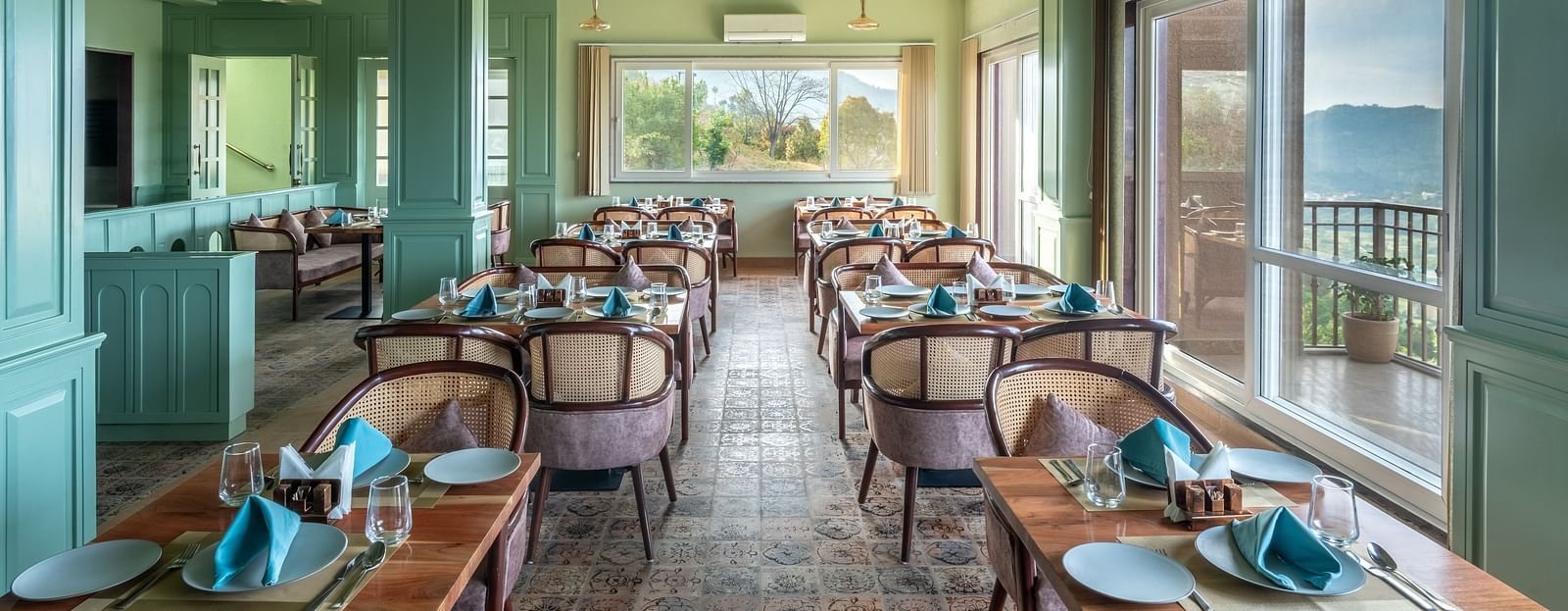 an image of a dining space filled with natural light, chairs and tables are placed with cutlery and hand towels at Mountoria Retreat, Naukuchiatal