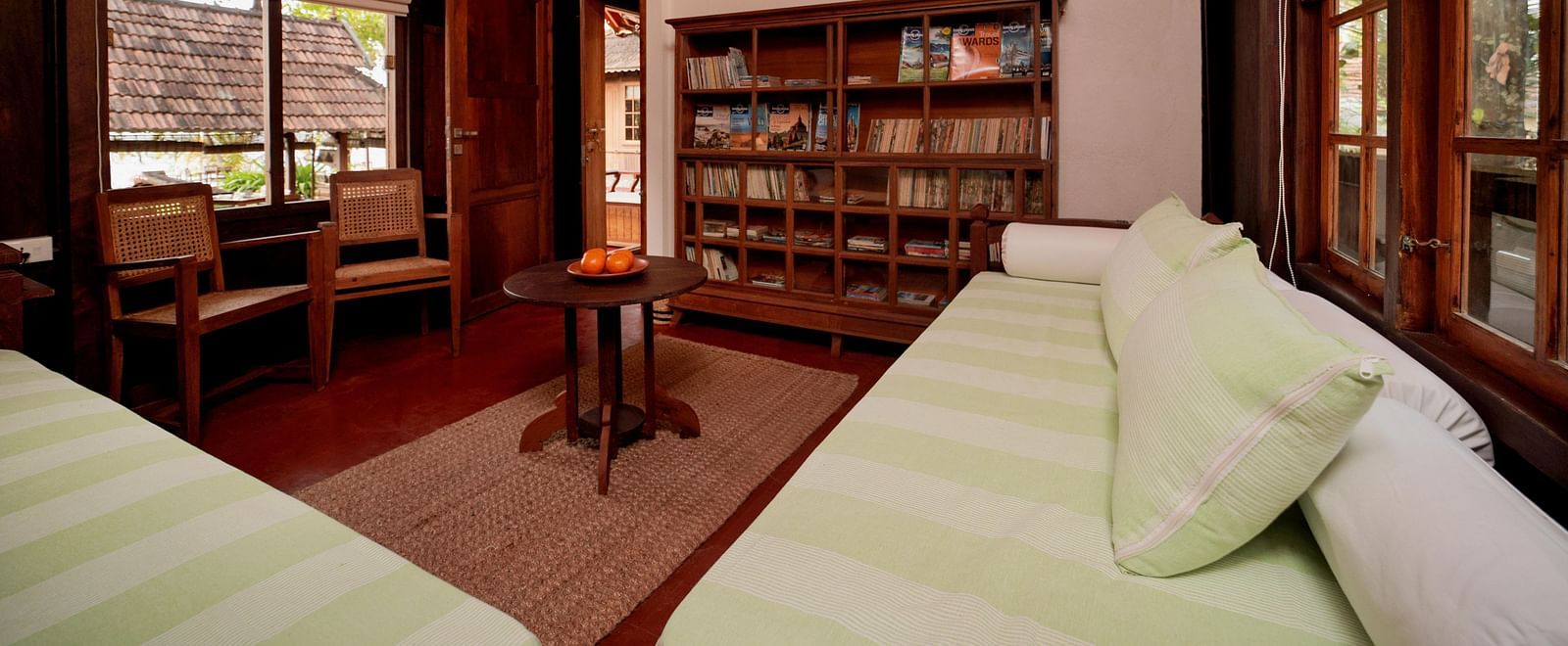 A view of the living room with comfortable seating and a book shelf  at Heritage Cottage at Samiira on Ashtamudi Lake.