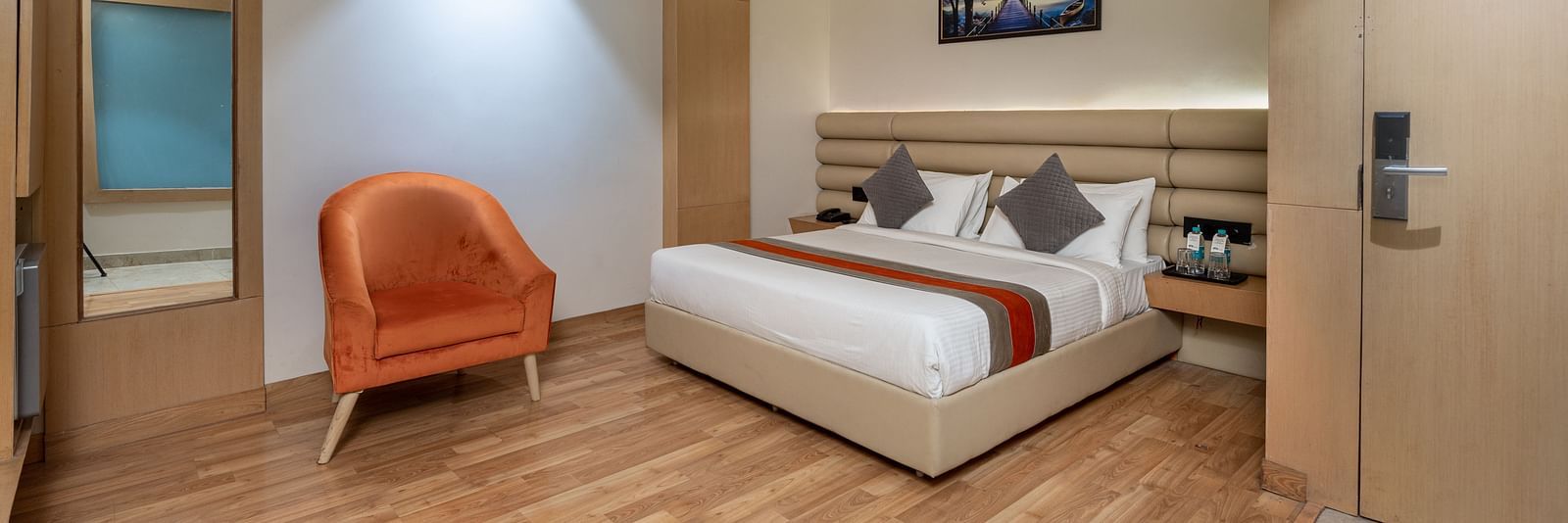 The deluxe room at DLS Hotel Arihant, Haridwar with a bed, bed side tables, a chair, and other room amenities