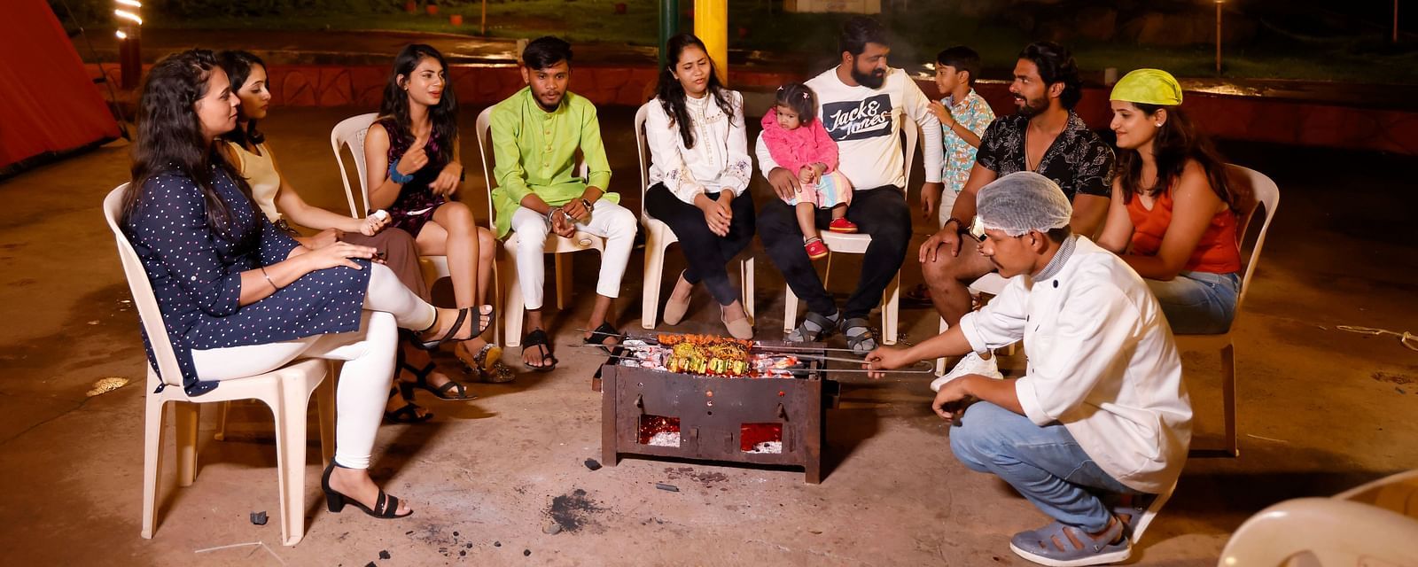 Group of friends enjoying a bonfire at a camping site in the evening | Diamond Parks, Pune