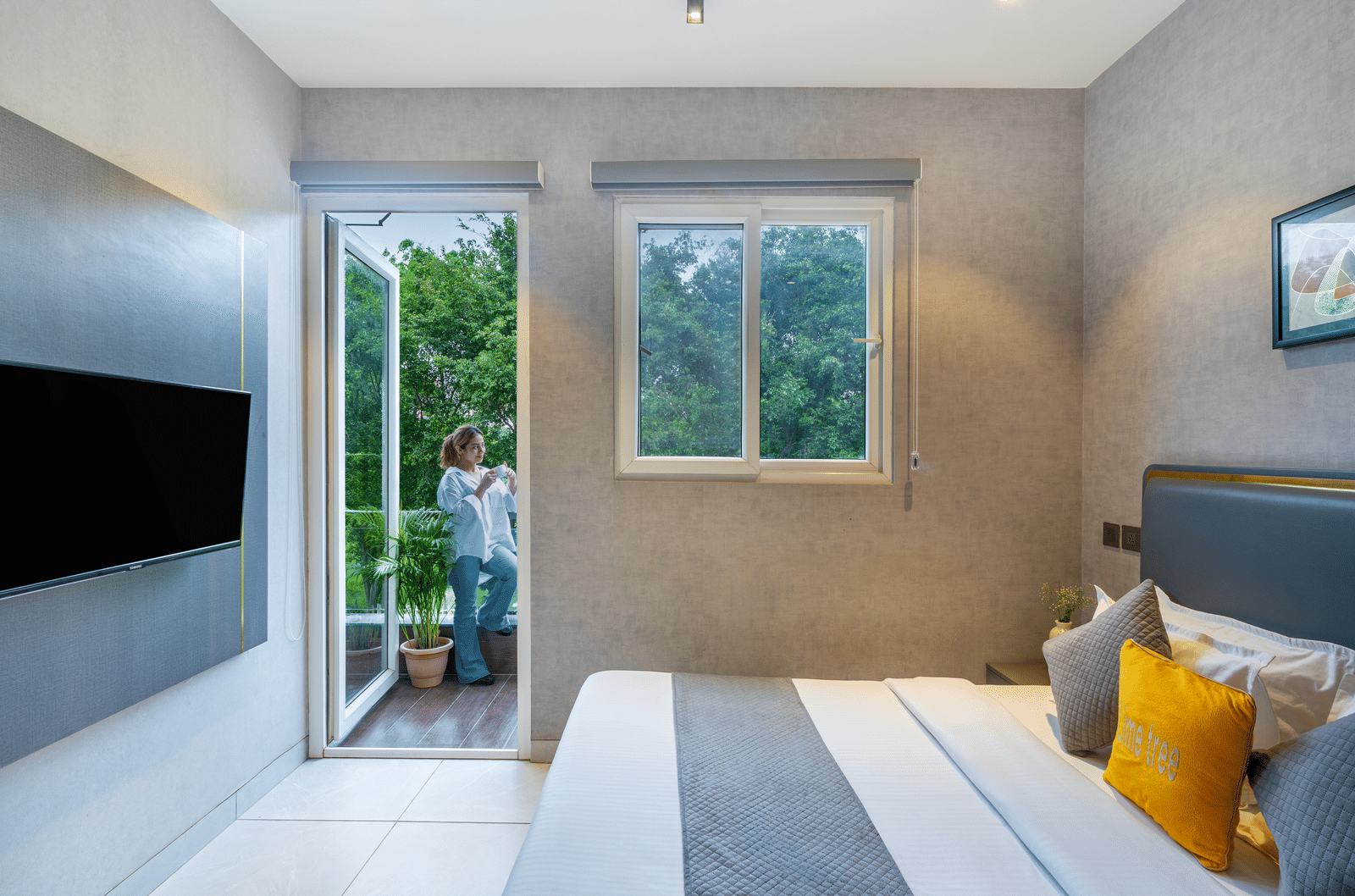 Modern room with bed, wall-mounted TV, and window view at Lime Tree Hotel & Stays Greater Noida Nearby India Expo Centre & Mart.