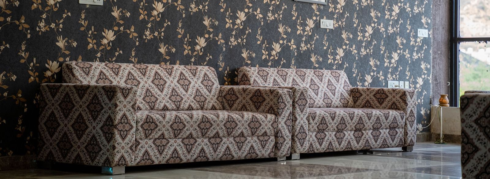 Close-up view of two sofas in the lobby of Bamboo Saa Mulberry Resort in Pushkar with Rajasthani elements-incorporated interiors.