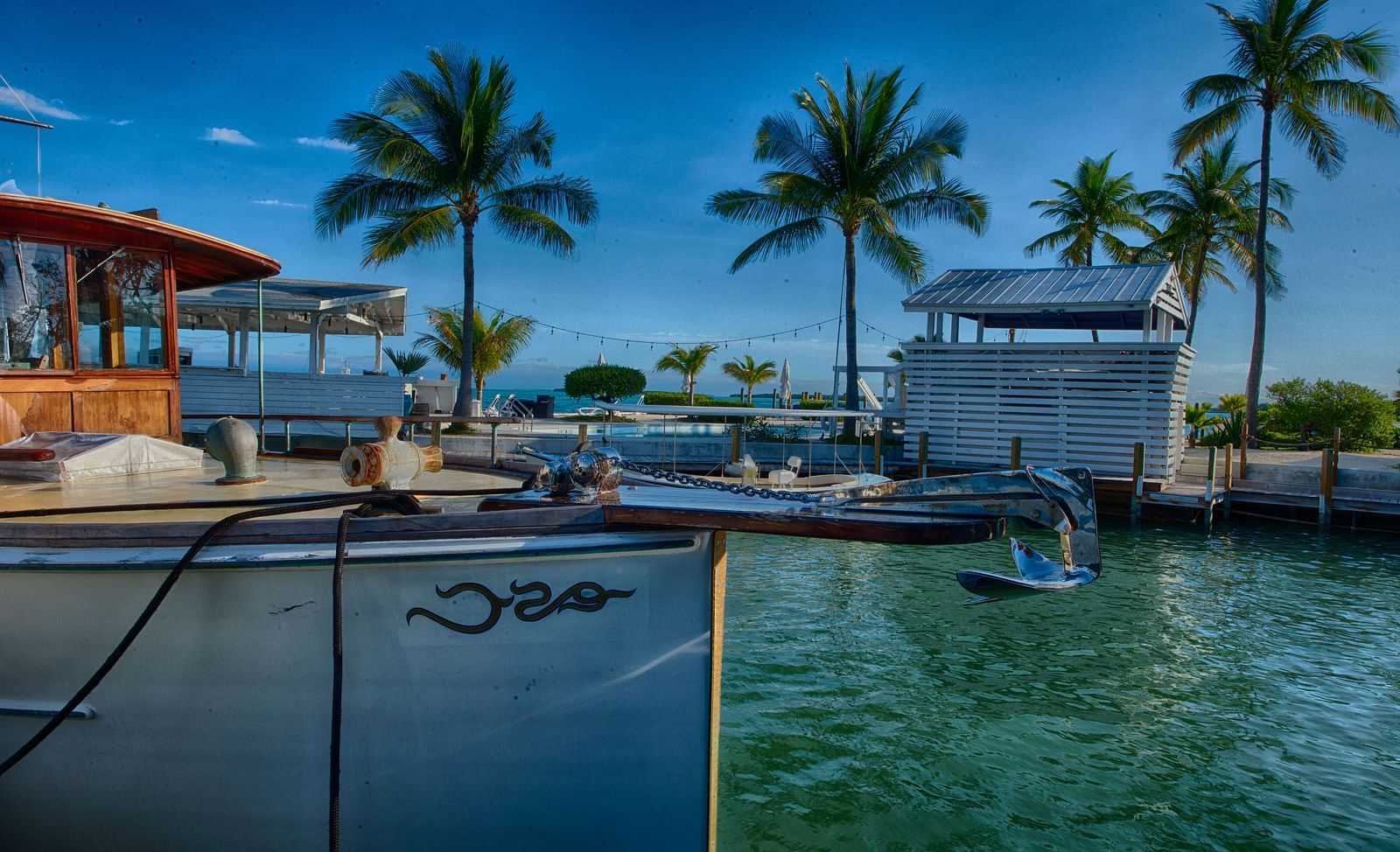 View of Casa Morada's waterfront with a docked boat, palm trees, and resort buildings in the background.