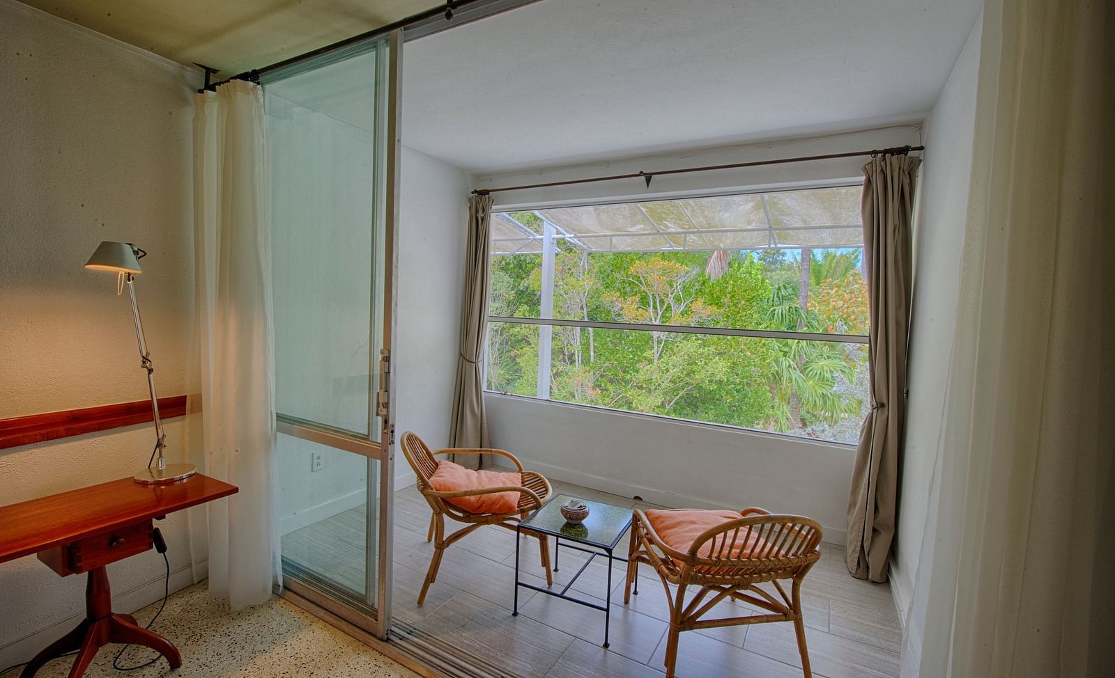 Room at Casa Morada with a desk, two chairs, and a large window overlooking greenery.