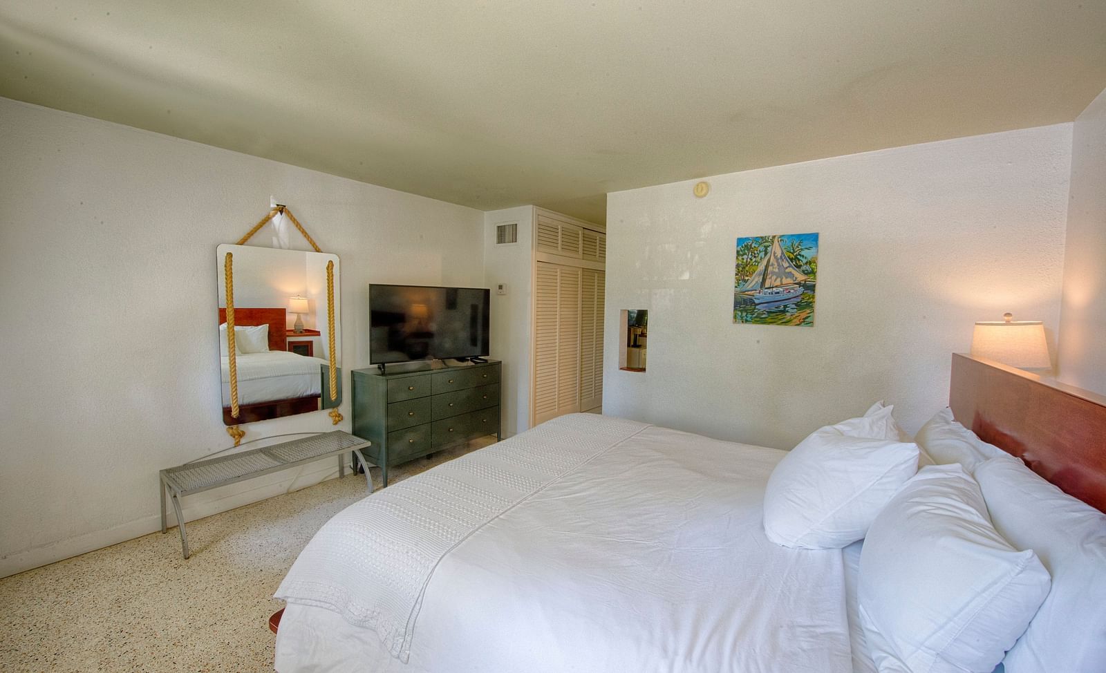 White bed in a Casa Morada suite with a mirror, open floor space, and subtle lighting.