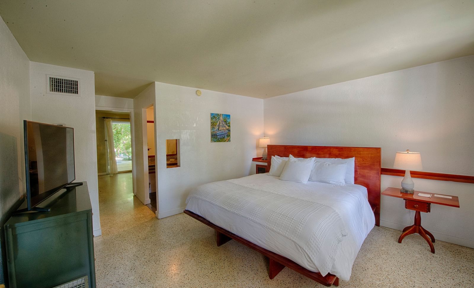 Casa Morada's bedroom with a king bed, wooden headboard, wall art, and a TV.
