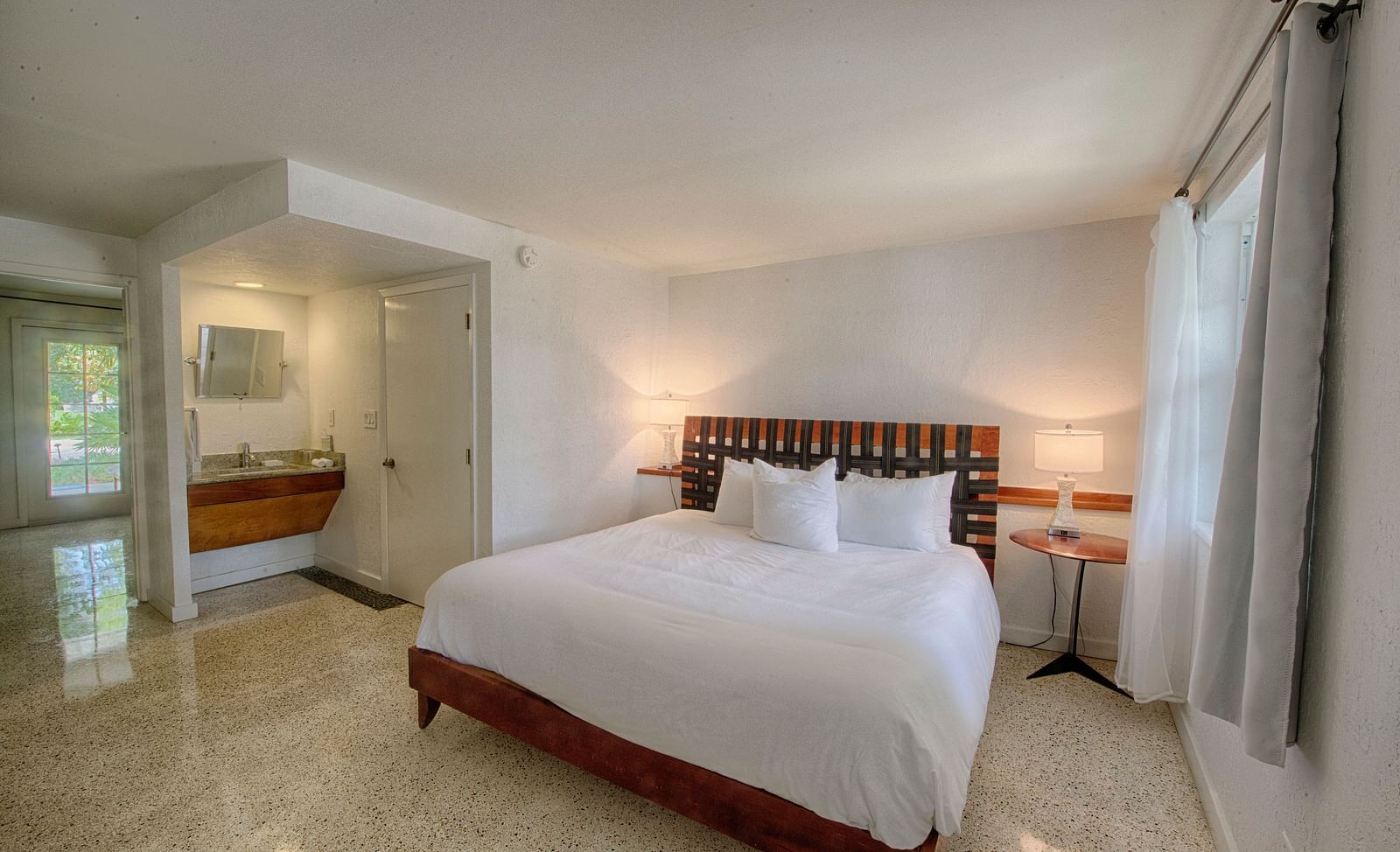 Bedroom at Casa Morada with a king bed, wooden headboard, and a sitting area near large windows.