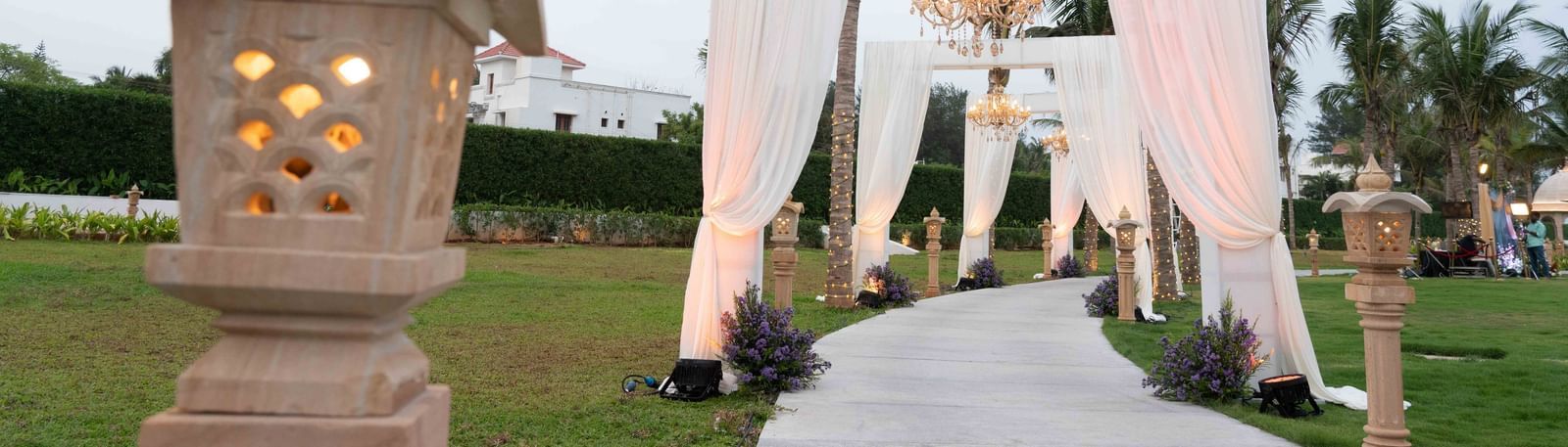 An pathway in the lawn with a lamp post and towering arches - Kaldan Samudhra Palace