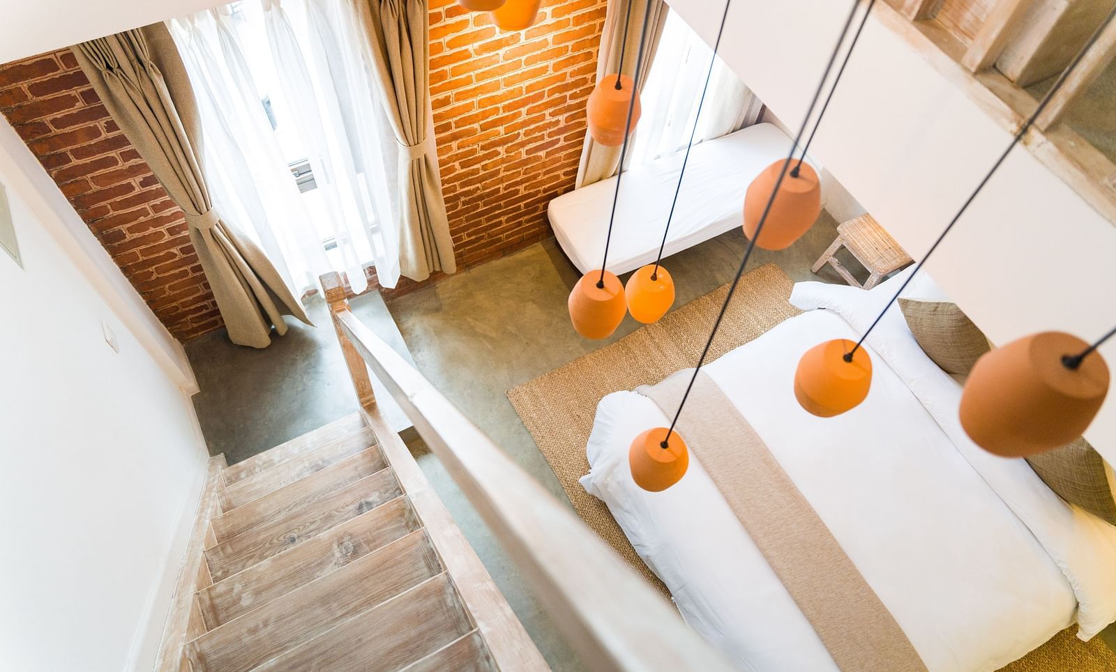 An aerial shot of the deluxe loft room with a staircase and chandelier hanging above it - The Nanee