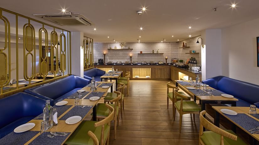 A chic dining area at our hotel with blue couches, glass tables, upholstered chairs and cosy lighting - Grand Continent, Brookefield