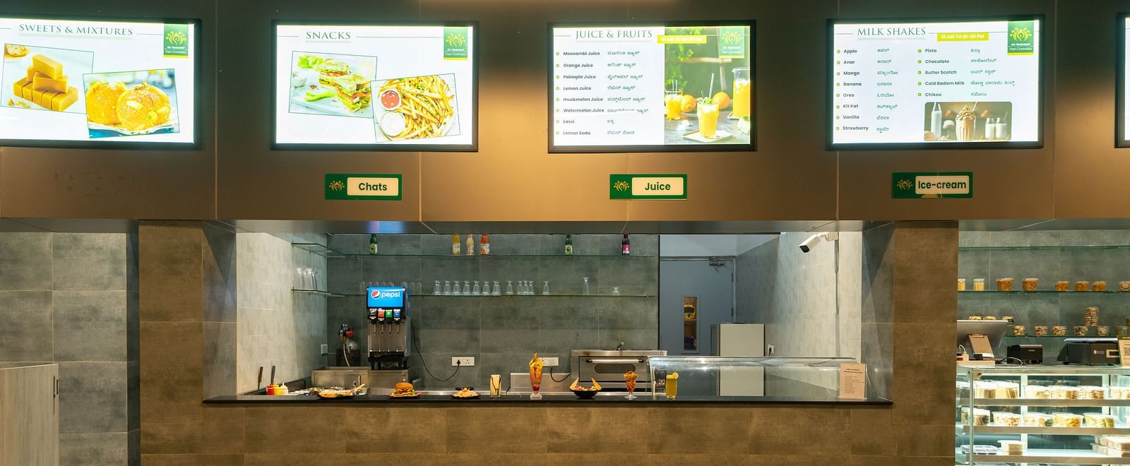 Food counter at Hari Govinda's, with display boards mounted above the counter on the wall