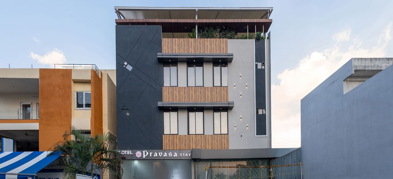 The facade of a modern multi-storey Pravasa Stay Dewas Naka, Indore under the blue sky.