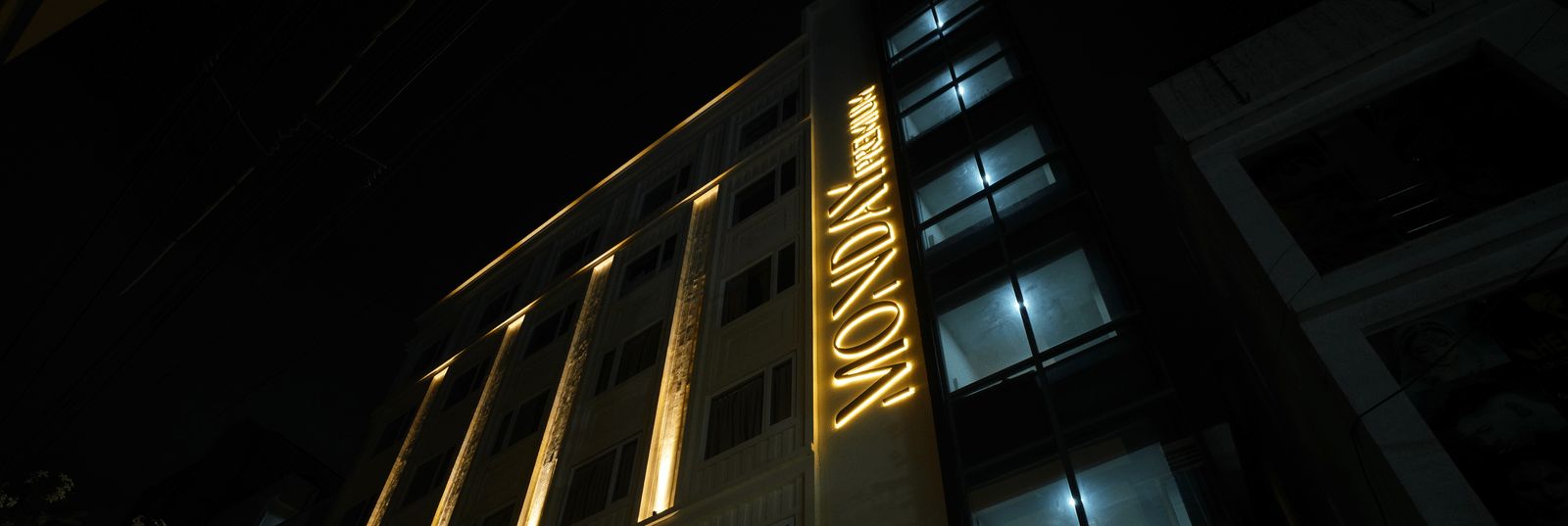  Striking night view of the Monday Premium, Madhapur, façade, with up-lighting highlighting tall architectural pillars and multiple floors. 