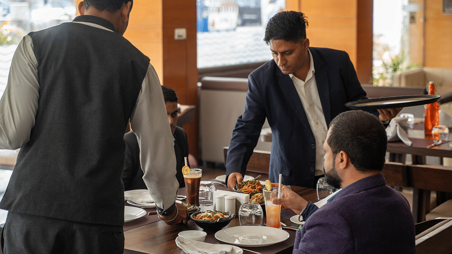 Hotel staff providing attentive service to seated guests in a restaurant - Hotel Udai Median, Udaipur.