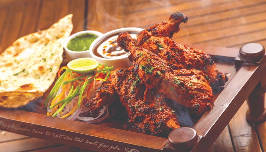 a chicken dish with naan and dips on a table - Caravela Beach Resort Goa