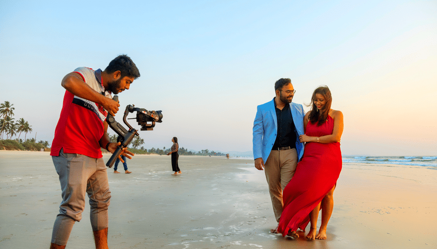 a couple being photographed on the beach with the evening sun in the background - Caravela Beach Resort Goa